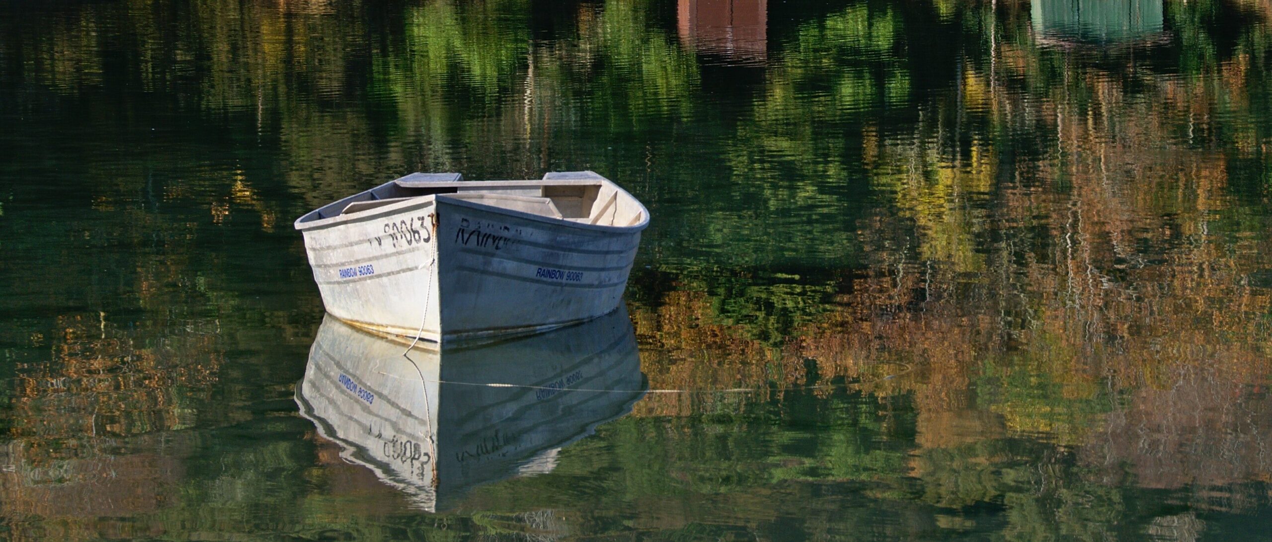 Image of a row boat on a serene pond with still water. 